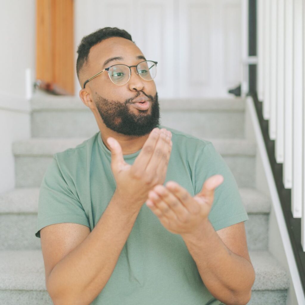 Black man with glasses communicating through sign language. Sign language is used a a facial expressions sensory activity for babies to learn language.