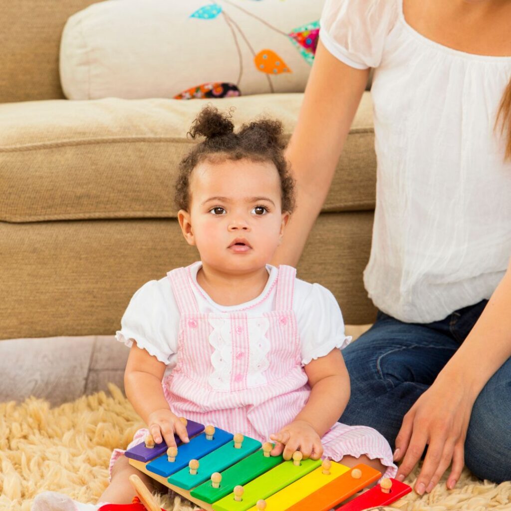 baby girl playing xylophone as a sensory music activity