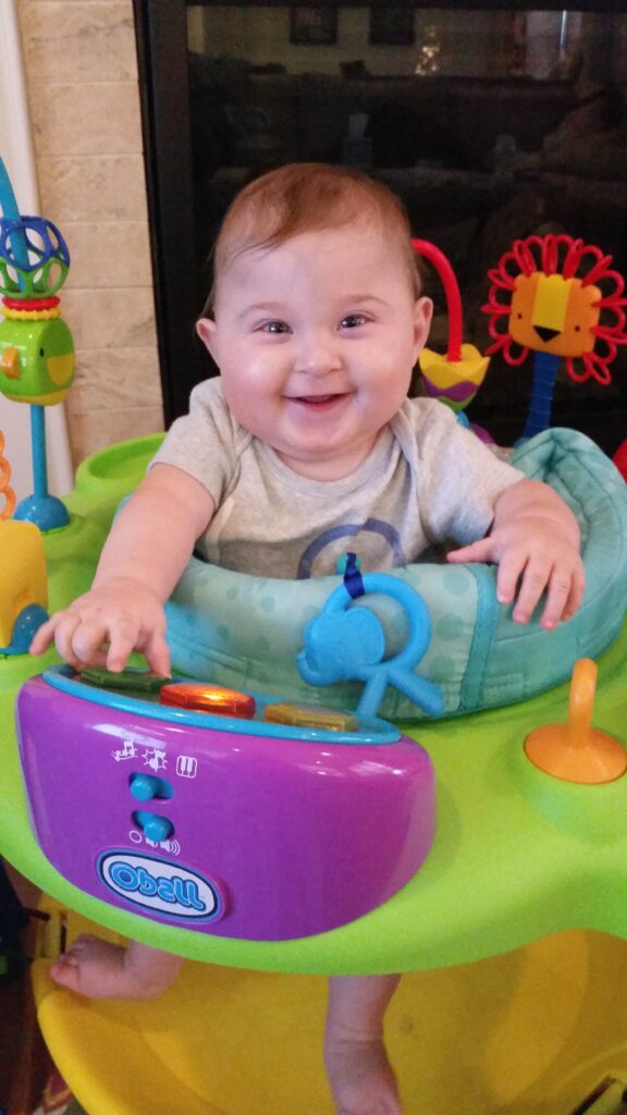 a baby smiles and sit in an exercise chair