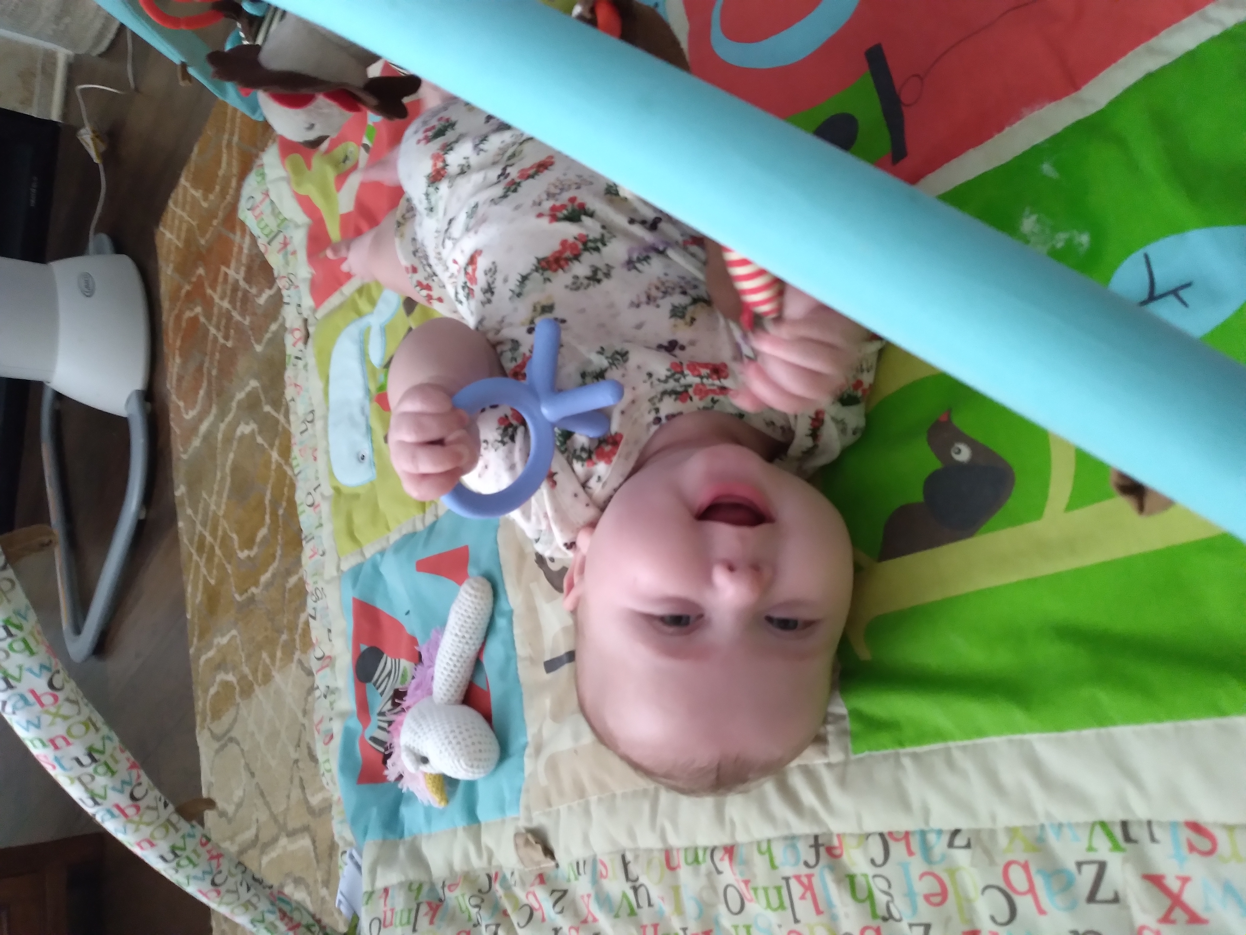a baby smiling and playing on their play mat