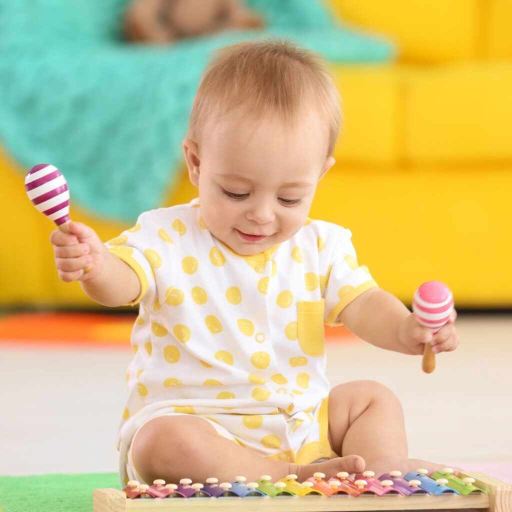 baby playing a xylophone and a rattle for a sensory music activity
