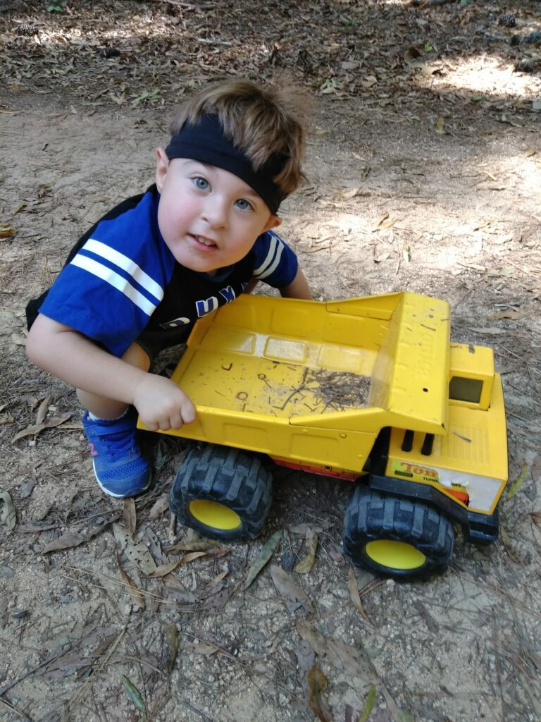 a boy playing outside with a jumbo construction vehicle for a car and truck activity