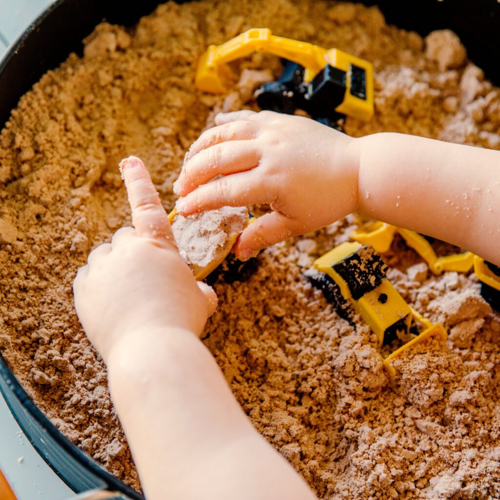 a kid playing with construction vehicles sand activities in the sand box