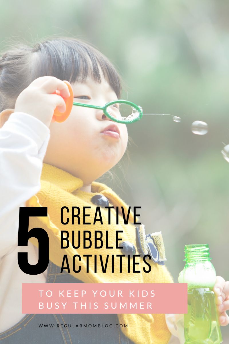 a little girl is in a backyard during the summer and blows bubbles for bubble activities for kids.