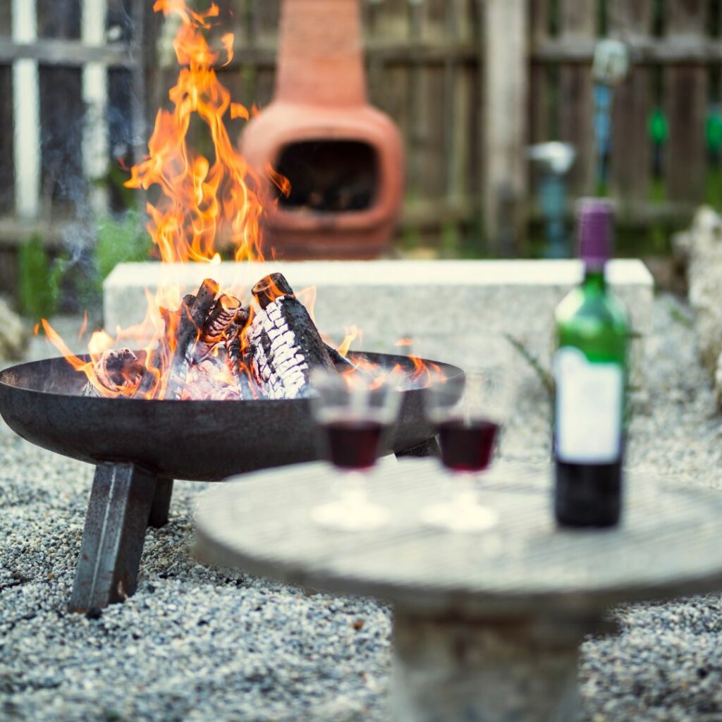 an outdoor fire pit with two wine glasses in the foreground
