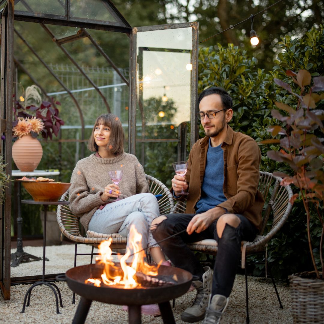 a couple enjoys drinks in front of their fire pit in their garden