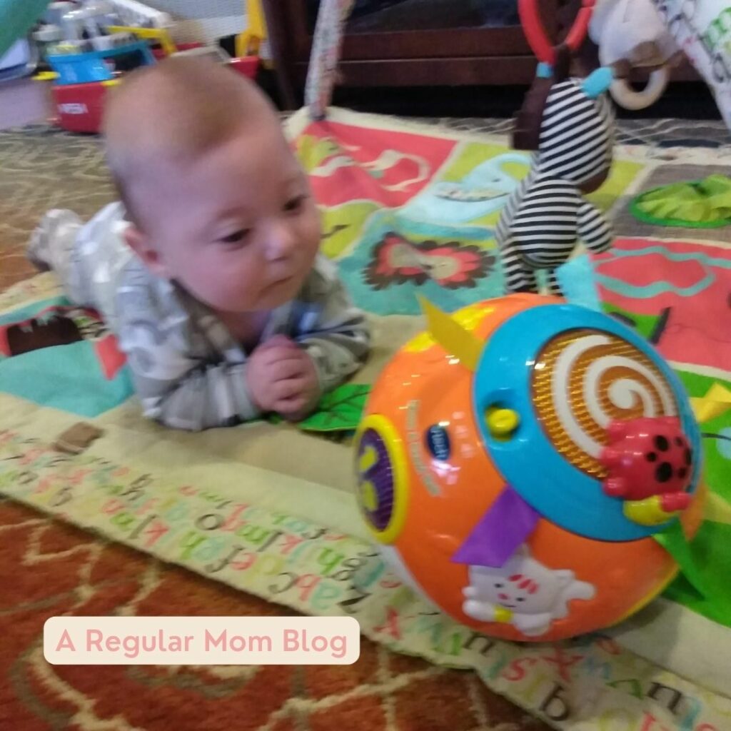 a baby laying on a play mat and looking at brightly colored ball during a sensory game