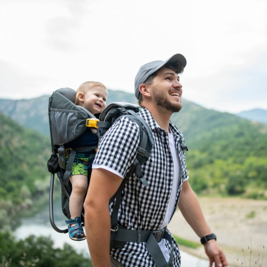 a father takes his baby hiking in a baby carrier to explore hearing sensory activities outside in nature