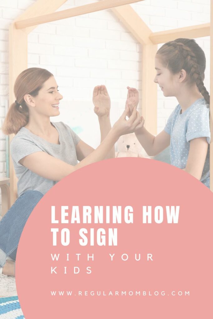 a woman and her daughter sit in a bedroom and learn how to sign the letter C in ASL