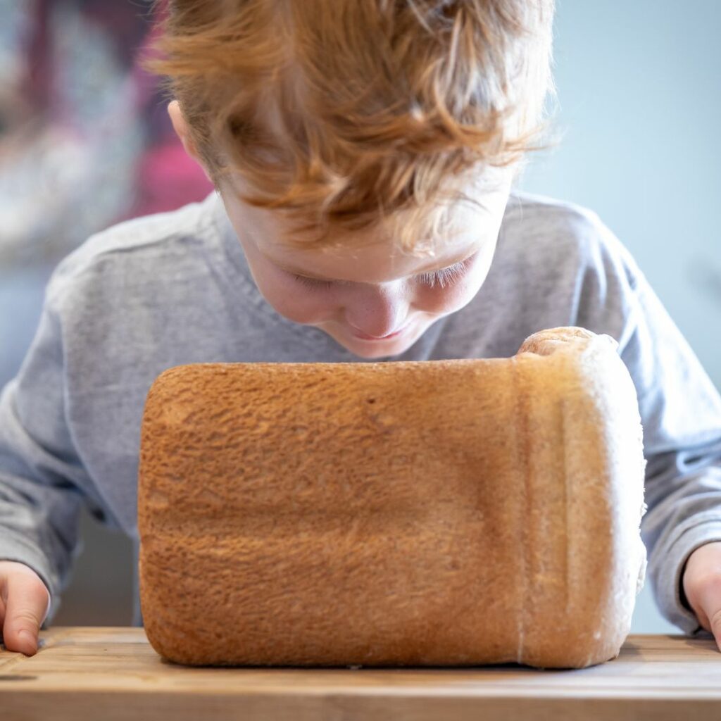 a boy stands at a counter and smells bread for a smell sensory activity