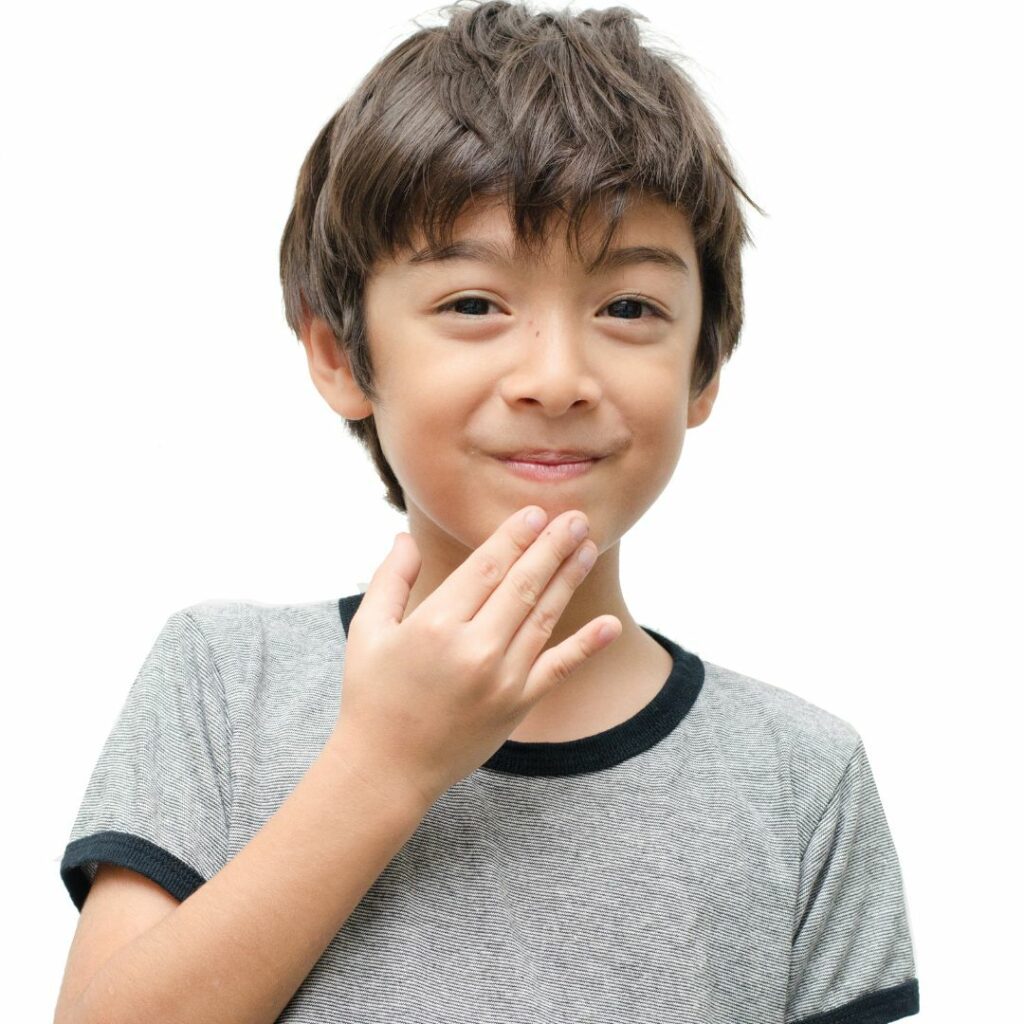 a boy stands in front of a white background and does the ASL sign for thanks for demonstrate why it's important to teach sign language to kids.