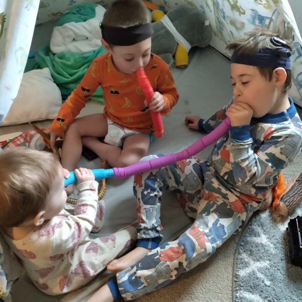 three young kids sitting on the floor and playing with each other two kids have cochlear implants