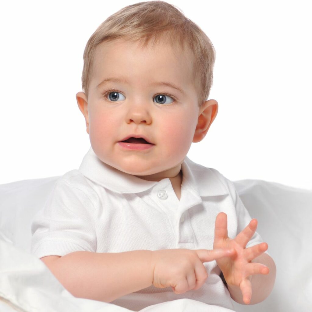 a baby sits up and does an asl sign with his hands