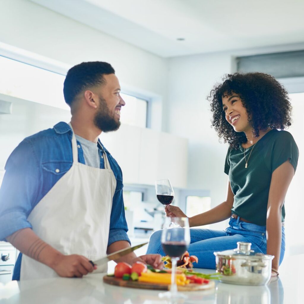 a man and woman sit at the kitchen counter and cook together for a creative at home date night idea
