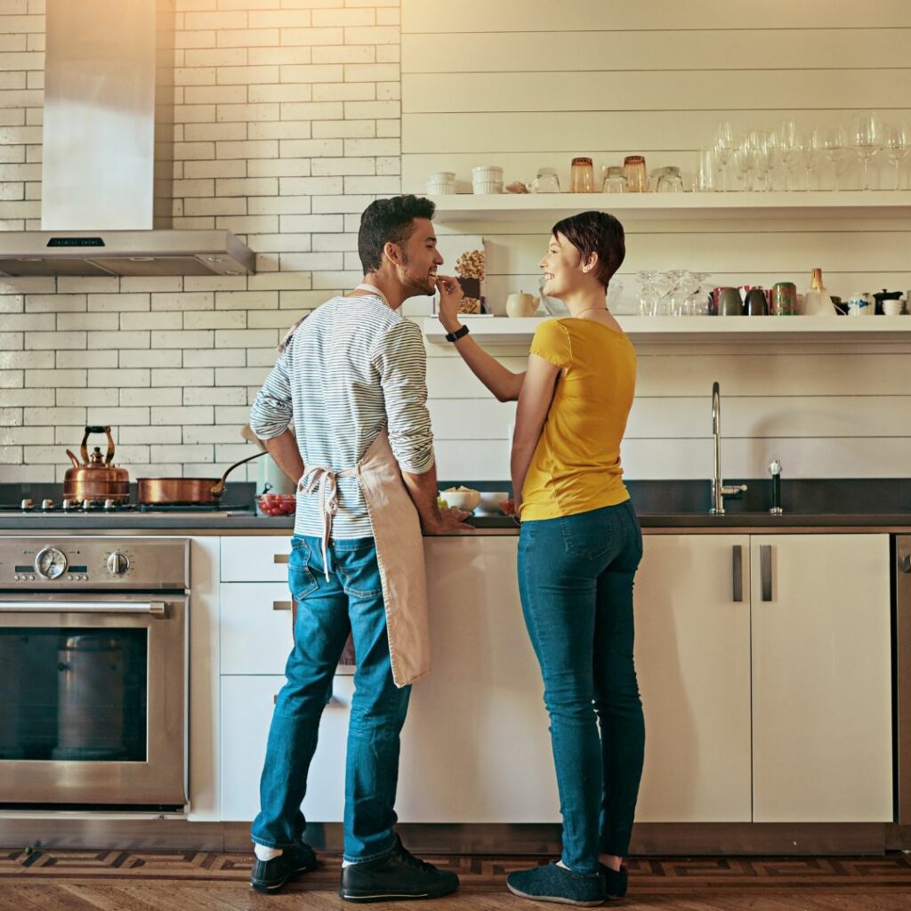 a couple stands in the kitchen and cooks together for a dinner date night at home