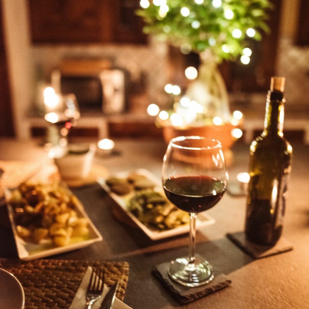 a picture of appetizers and a glass of wine on a table surrounded by lights for a dinner date night at home